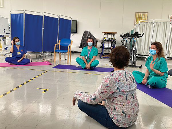 people in scrubs sitting on yoga mats on the floor